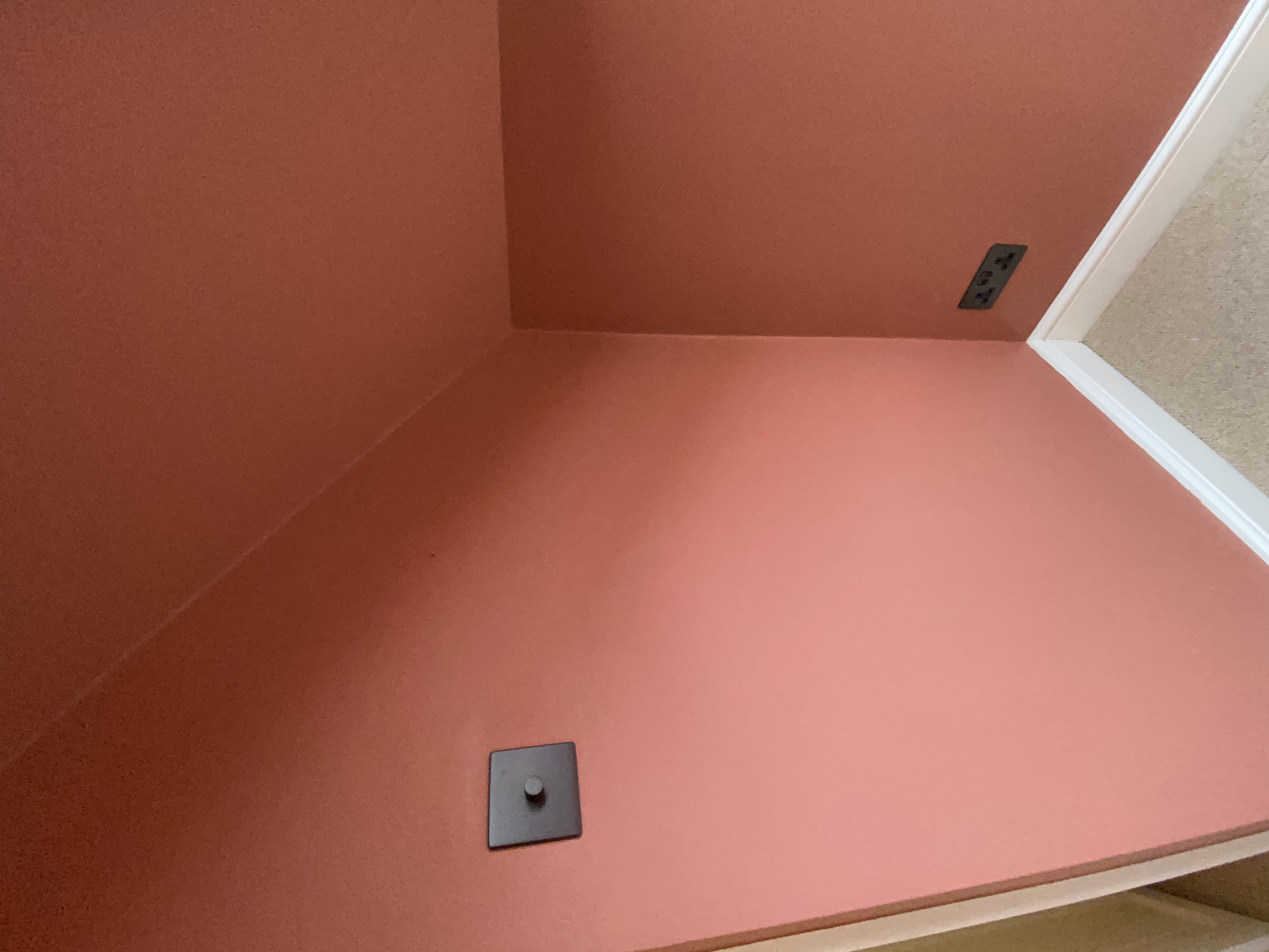 Corner of a terracotta room showing a built-in storage nook and matte wall finish